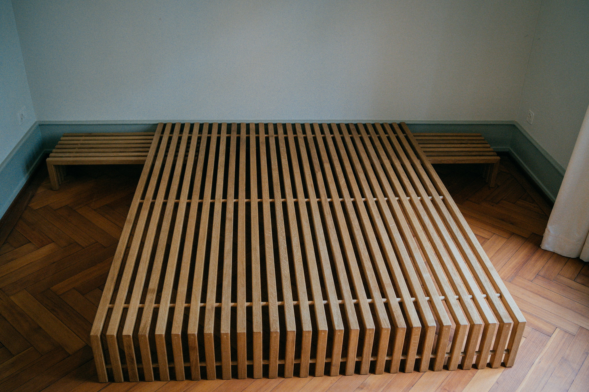 Bett PENTOS von vorn: Lattenpaket aus Schweizer Eiche, links und rechts ein Nachttisch an der Wand